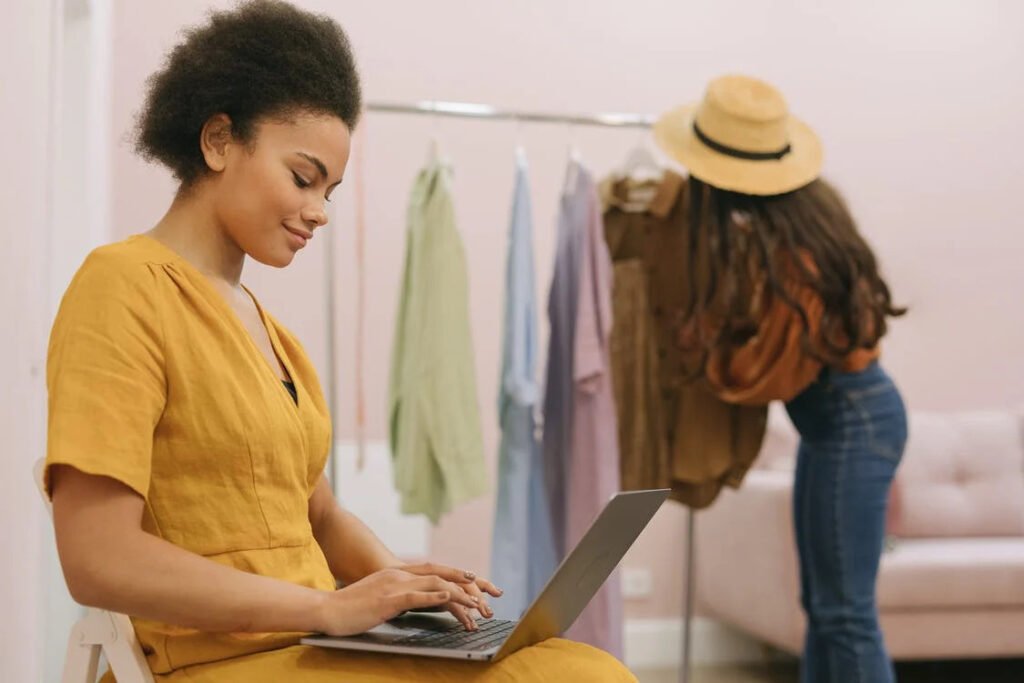 mulher no computador com arara de roupas ao fundo