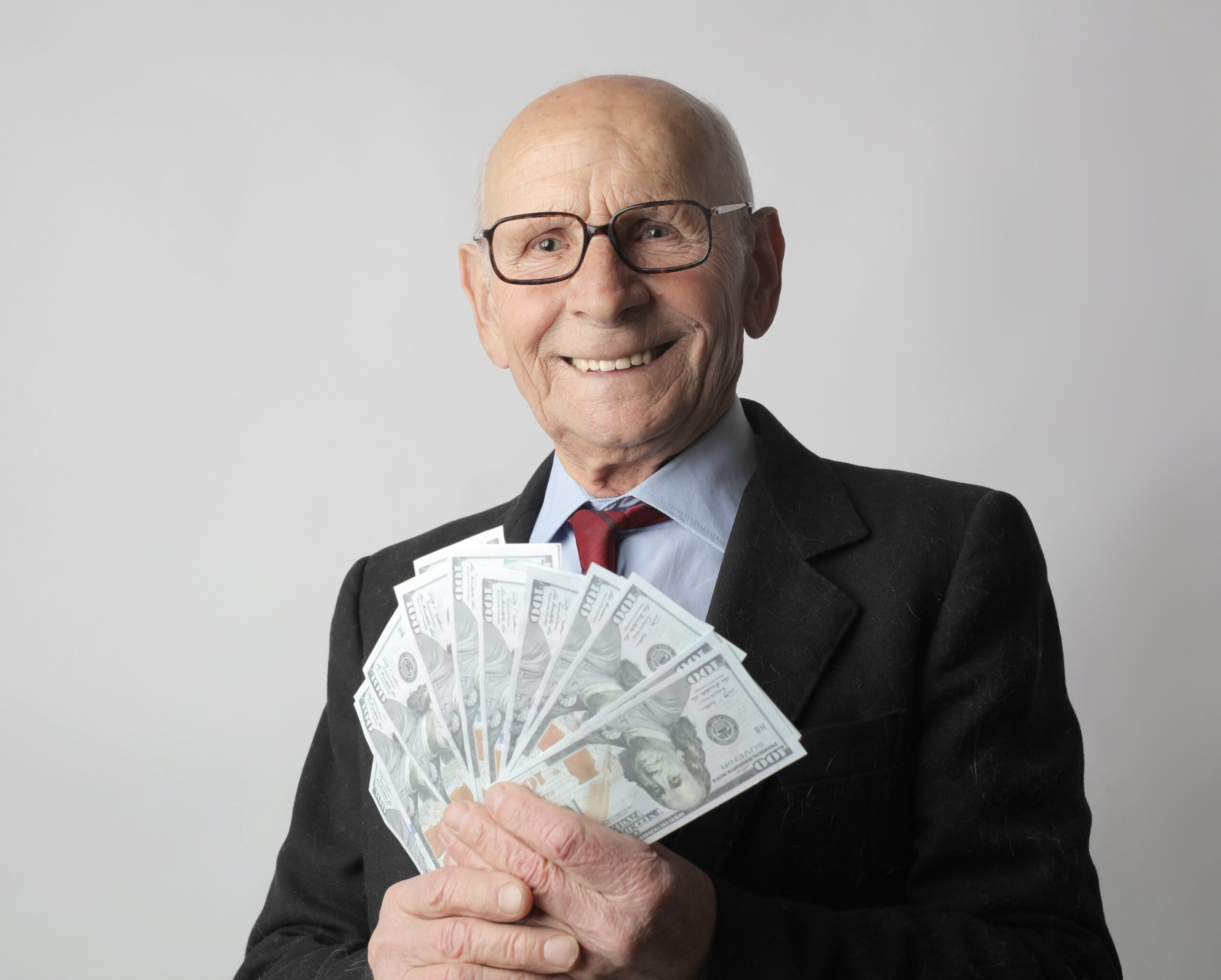 empréstimo com garantia de imóvel idoso segurando notas de dinheiro